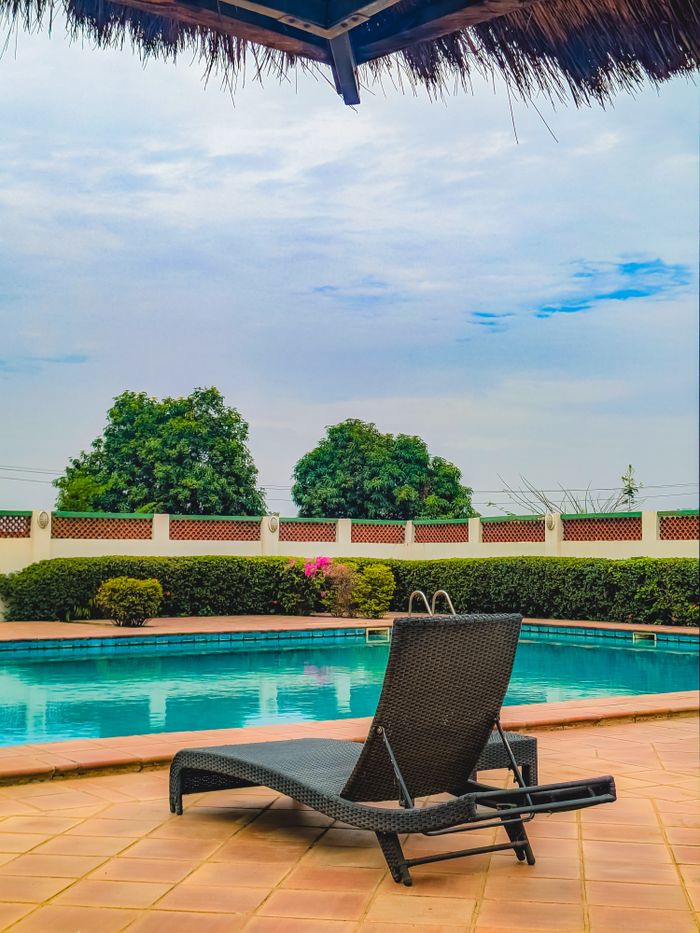 A serene view of a poolside lounge area under a blue sky in Abuja, Nigeria.
